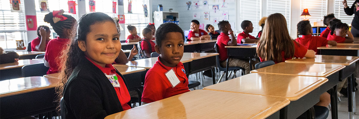 Two students sitting at their desks pose for the camera